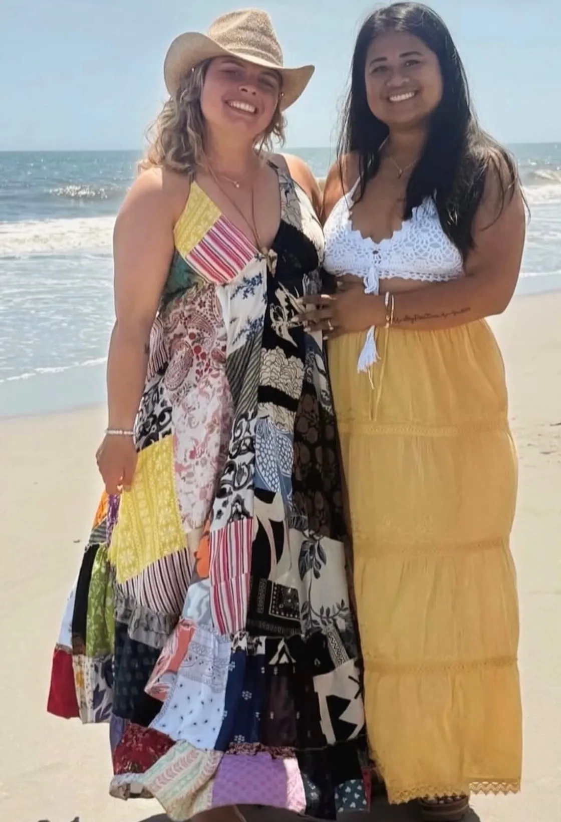 Two people wearing colorful bohemian-style clothing while standing at the beach.