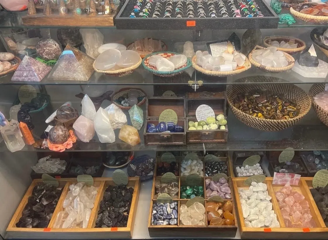 Crystals, polished stones, rings, and gemstone pieces arranged in a glass display case.