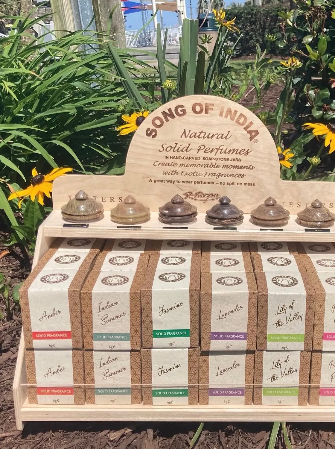 Natural solid fragrances displayed in small carved containers outdoors.
